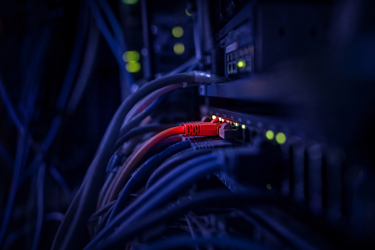 Cavi di rete aggrovigliati in una sala server, uno rosso tra i blu, metafora di un hosting compromesso